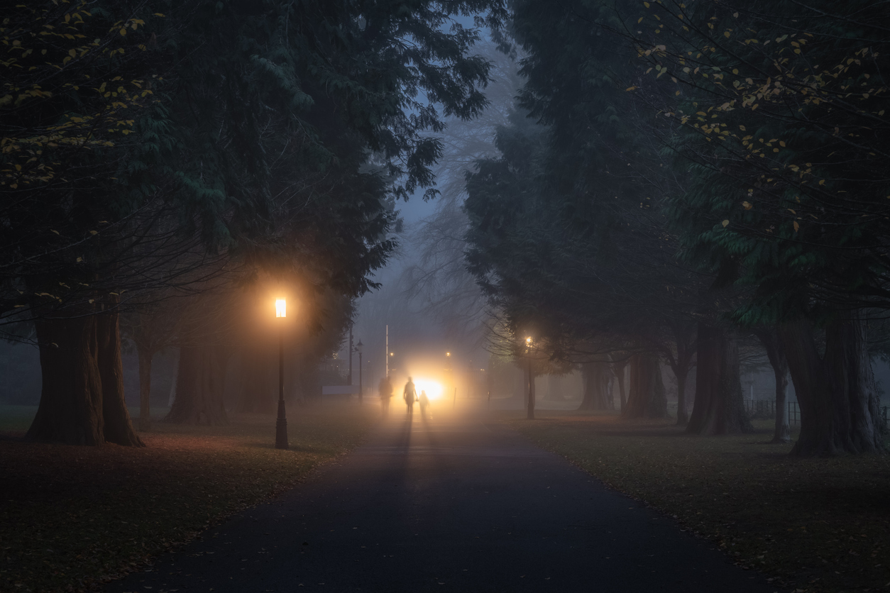 Silueta de personas caminando en una noche con niebla